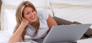 Beautiful Blond Young Woman Working On Her Laptop Computer In A Hotel Room